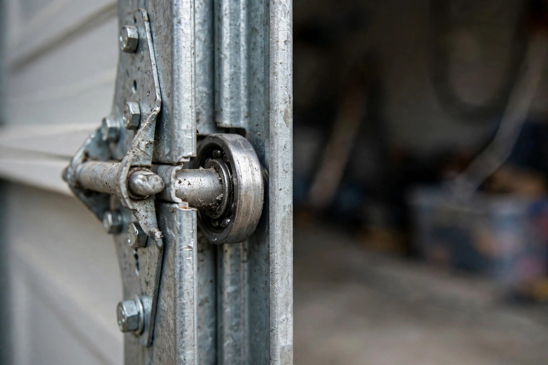 Close-up of garage door rollers inside a steel track with hinges and bolts